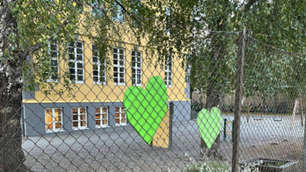 Foto av grønne hjerter på et gjerde rundt en skole.
