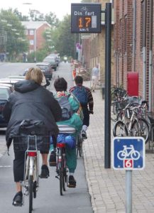 Figur 3. Grønn bølge og visning av fart slik syklisten kan tilpasse farten sin til den grønne bølgen (Odense kommune 2009). Figur 3. Grønn bølge og visning av fart slik syklisten kan tilpasse farten sin til den grønne bølgen (Odense kommune 2009).
