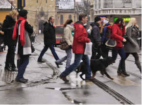 Fotoet viser flere gående som krysser en bygate.