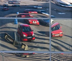 Bilde tatt gjennom et speil eller speilende vindu som viser parkerte biler.