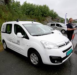 Hvit elvarebil parkert utendørs.