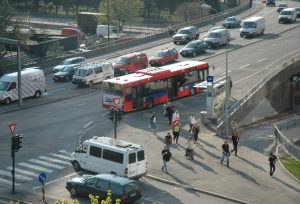bilde av gatekryss med gangfelt og en gruppe mennesker som går fra en bussholdeplass.