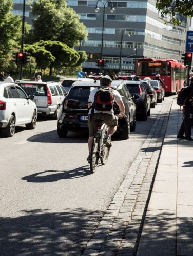 syklist som sykler på en trafikkert gate.