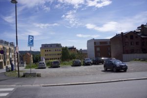 et bilde av biler parkert i en parkeringsplass ved en vei.