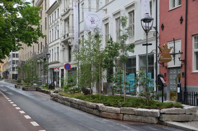 Foto av Kirkegata i Oslo med utvidede fortau med beplantede steinbed, og smalere kj&oslash;rebane kun for syklister.
