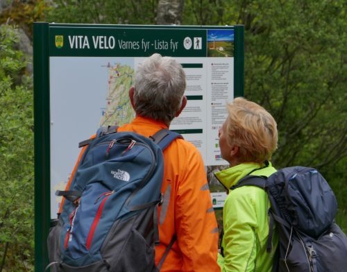 Foto av to syklister som ser på en tavle som inneholder et sykkelkart og stedsinformasjon.