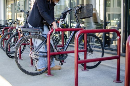 Bildet viser dame som l&aring;ser ramme og hjul p&aring; sykkelen sin fast i et sykkelstativ med kjettingl&aring;s