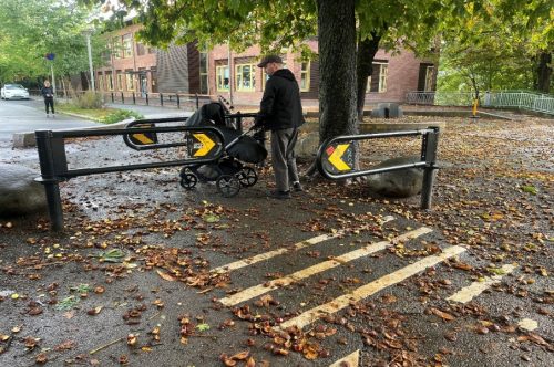 en mann med barnevogn g&aring;r gjennom saksebommer. Bommene er plassert etter hverandre i annenhver retning slik at man m&aring; ta en krapp sving. Bakken er full av kastanjer og l&oslash;v som kan inneb&aelig;re ubehag og risiko for fall.